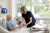 A nurse provides attentive care to an elderly male patient in a hospital bed, holding his hand amid medical equipment and natural light.