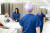 A nurse monitors an older patient’s blood pressure in a bright, private hospital room, while staff ensure attentive care nearby.