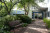 A welcoming brick pathway with greenery leads to Burnside Hospital’s entrance, with shaded seating and the hospital sign visible.