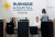 At Burnside Hospital, Stepney, two staff members sit at the reception desk while a visitor is assisted. The hospital name and logo are visible.
