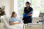 A patient in a well-lit hospital room smiles while conversing with a nurse. Fresh flowers and modern medical equipment are nearby.