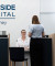 A friendly receptionist in a white shirt welcomes a visitor at a modern, professional hospital reception desk.