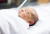 A newborn, securely wrapped in a white blanket, rests calmly on a hospital bed under gentle natural light, ensuring comfort and safety.