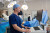 A skilled clinician in sterile blue scrubs uses a computer workstation in a modern, well-equipped private hospital operating room.