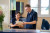 Two healthcare professionals in navy uniforms collaborate at a reception desk in a bright, welcoming hospital environment.