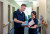 Two healthcare professionals in navy uniforms review documents together in a bright hospital hallway, smiling and engaged.