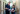 Two healthcare professionals in navy uniforms review documents together in a bright hospital hallway, smiling and engaged.