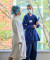 A healthcare professional in blue scrubs speaks with a masked patient by a window, offering support in a calm hospital setting.