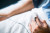 A hand rests comfortably on a hospital bed with a pulse oximeter on the finger, gently monitoring oxygen levels under a white blanket.