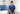 A healthcare professional in blue scrubs stands in a well-lit hospital room beside a treatment chair, IV equipment, and window blinds.