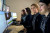 Four women in matching uniforms work at desks with multiple computer monitors in a well-lit, professional office environment.