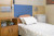 A clean, well-prepared hospital bed with white linens sits beside wooden cabinets; modern equipment is neatly arranged above.