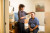 A healthcare professional gently places medical electrodes on a smiling patient’s forehead in a bright, comfortable hospital room.