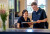 Two healthcare professionals in navy uniforms review documents at a welcoming reception desk with fresh flowers and natural light.